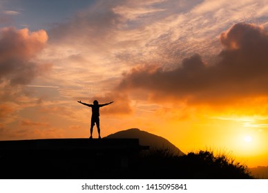 Happiness And Freedom In Nature. Man On A Mountaintop Facing Sunset.