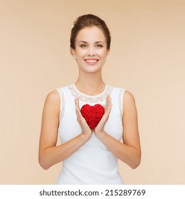 Happiness, Health, Charity And Love Concept - Smiling Woman In White Dress With Red Heart Over Beige Background