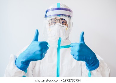 Happiness healthcare worker in PPE suit showing thumb up gesture while working in hospital during covid-19 pandemic.