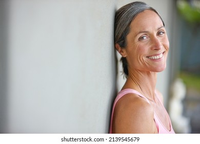 Happiness is an inside job. Portrait of an attractive mature woman in gymwear leaning against a gray wall. - Shutterstock ID 2139545679