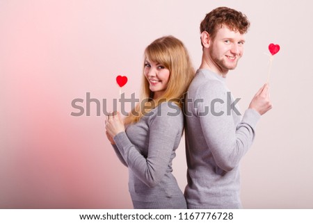 Happiness in love. Lovely charming couple smiling. Happy joyful woman and man holding little hearts on sticks. Two people with sign symbol of good relationship feelings.