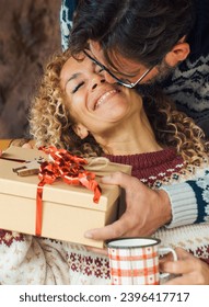 Happiness and love people in christmas gift exchange leisure activity at home. Man giving surprise present to an overjoyed and excited woman sitting on the sofa. Winter holiday celebration indoor - Shutterstock ID 2396417717
