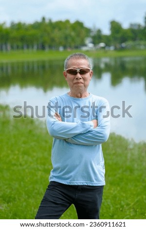 Happiness in nature, elderly asian man in blue shirt blissful time in the park, nature's comfort, parkside relaxation, peaceful moments, refreshing break