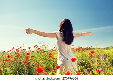 happiness, nature, summer, vacation and people concept - young woman dancing on poppy field from back - Powered by Shutterstock