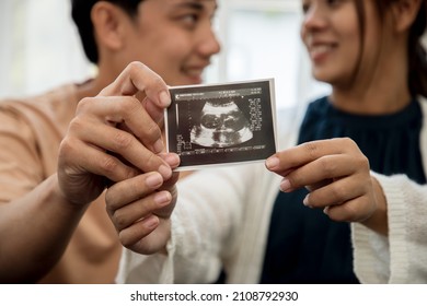 Happiness Of A Pregnant Woman And Her Husband In The Bedroom With The Ultrasound Film Of The Fetus That Shows The Results That The Child Is Healthy. Concept Of Preparing For A Family And Succession.