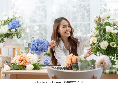 happiness smiling young lady making flower vase.Self employed florist working at flower shop.young asian florist making list from client order to arrange flower bouquet vase delivery
