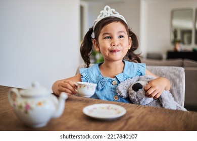 Happiness, Tea Party And Child In Her Home, Playing, Having Fun With Tea Set And Wearing A Crown. Creativity, Imagination And Young Asian Girl Enjoying Toys, Teddy Bear And Toy Kitchen Utensils