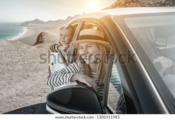 Happiness travelers\
mother and son, sitting in white car and look on beautiful seascape\
coastline view in sunny day. Freedom, Family, travel, nature,\
journey concept.
