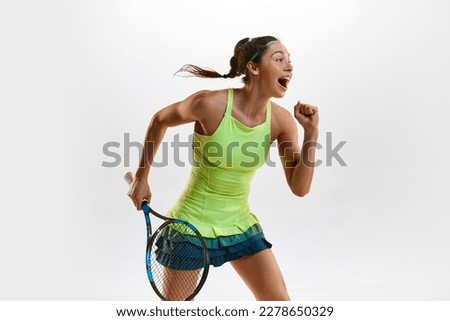 Happiness. Winner. Portrait of young woman, professional female tennis player in uniform posing with tennis racket against white studio background. Concept of professional sport, movement, action. Ad