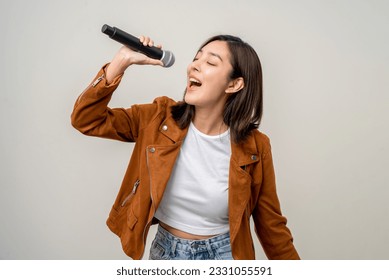 Happiness young asian woman singing song. Artist vocalist singer on isolated background. Confident woman public speaking talking with microphone in studio. - Shutterstock ID 2331055591