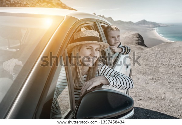 Happiness young woman in hat with her son\
sitting in white car and looking on beautiful ocean coastline view.\
Freedom, Family, Travel, Journey, Trip,\
concept.