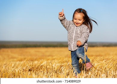 Happy 2 Year Old Girl Walking In A Summer Harvested Field