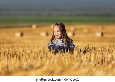 Happy 2 Year Old Girl Walking In A Summer Harvested Field