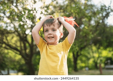 A happy 3-4 year old boy runs on the grass in the summer with a colorful pinwheel. Carefree childhood - Powered by Shutterstock