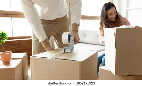 Happy 35s Married Couple Packing Personal Belongings, Sealing Big Cardboard Boxes With Adhesive Tape Preparing To Move From Rented House At Own New Home. Bank Loan For Young Family, Ownership Concept