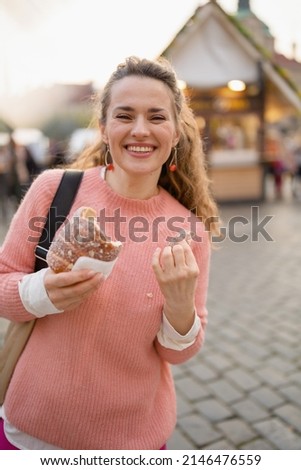 happy 40 years old woman at the fair in the city eating trdelnik.
