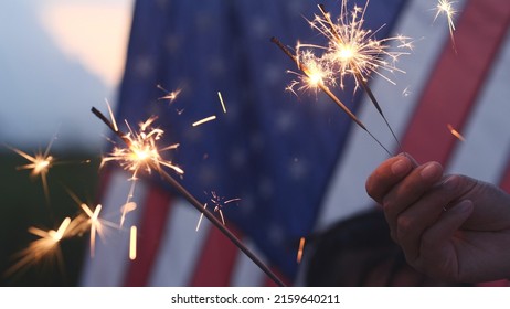 Happy 4th Of July Independence Day, Hand Holding Sparkler Fireworks USA Celebration With American Flag Nature Background. Concept Of Fourth Of July,Independence,Fireworks,Sparkler, Memorial,Veterans