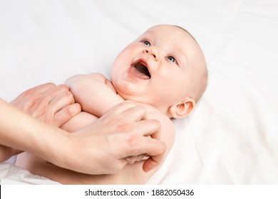 Happy 5-month Baby Boy Receiving Massage Therapy In Pediatric Clinic. Manual Therapist Manipulates Childs's Arms