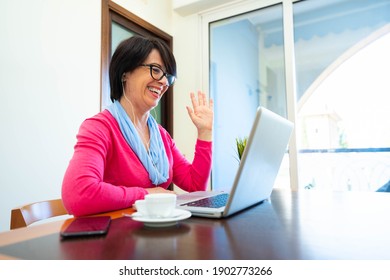 Happy 60s Older Mature Adult Woman Waving Hand Holding Digital Tablet Computer - Video Conference Calling By Social Distance Virtual Family Online Concept