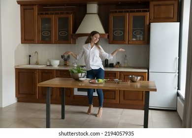 Happy Active Cooking Blogger Woman Dancing To Music At Kitchen Table With Fresh Vegetables, Organic Food Products;, Salad Ingredients, Enjoying Healthy Active Lifestyle, Having Fun