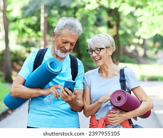 Happy active elderly couple having fun talking and bonding using a smartphone after having an exercise in park outdoors - Powered by Shutterstock