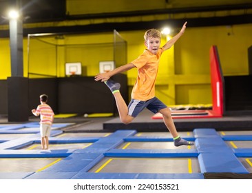Happy active emotional preteen boy bouncing on trampoline while having fun in indoor amusement park.. - Powered by Shutterstock