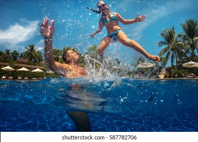 Happy Active Family Young Father And His Cute Daughter Adorable Toddler Girl Playing In A Swimming Pool Jumping Into The Water Enjoying Summer Vacation