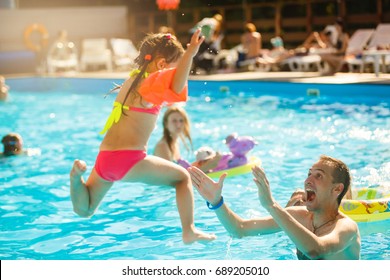 Happy Active Family Young Father And His Cute Daughter Adorable Toddler Girl Playing In A Swimming Pool Jumping Into The Water Enjoying Summer Vacation