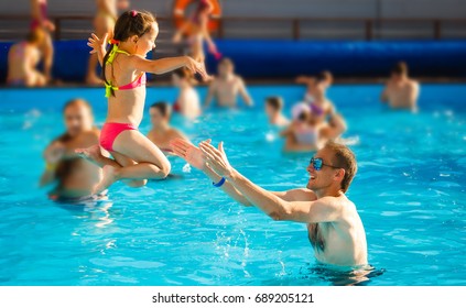 Happy Active Family Young Father And His Cute Daughter Adorable Toddler Girl Playing In A Swimming Pool Jumping Into The Water Enjoying Summer Vacation