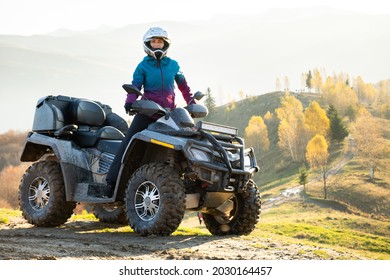Happy aktive weibliche Fahrer in Schutzhelm genießen extreme Reiten auf ATV Quad Motorrad im Herbst Berge bei Sonnenuntergang.