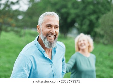 Happy active mid aged adult couple having fun walking running holding hands and bonding in park or nature outdoors - Powered by Shutterstock
