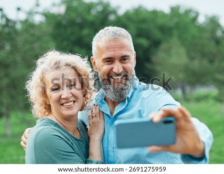 Happy active mid aged couple taking selfie in park or in nature outdoors. Love togetherness and acive seniors vitality concept