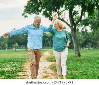 Happy active middle aged white couple having fun walking holding hands and bonding in park outdoors - Powered by Shutterstock