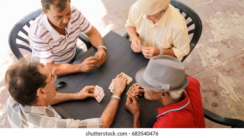 Happy Active Retired People, Old Hispanic Friends Having Fun, Seniors Playing Cards At Home.