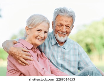 Happy active senior couple having fun talking and hugging sitting on a bench in park outdoors - Powered by Shutterstock