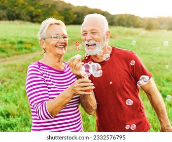 Happy active senior couple  having fun blowing soap bubbles outdoors - Powered by Shutterstock