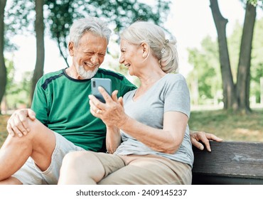 Happy active senior couple having fun using smartphone and wearing sportswear, after having an exercise sport activity outdoors - Powered by Shutterstock