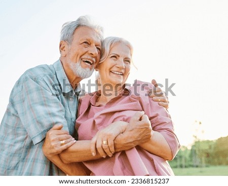 Happy active senior couple having fun talking and hugging in park outdoors