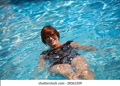 Happy Active Senior Woman ( 60s ) Swimming In Pool At Summer, Smiling.