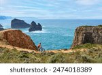 happy active senior woman cycling on the the rocky cliffs of the Vicentina coast of  Portugal near Sagres and Vila do Bispo 