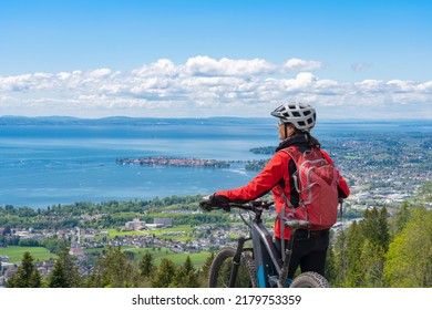 happy, active senior woman cycling above Lake Constance, Bodensee and  admiring the awesome view over Lake Constance to city of Lindau in background - Powered by Shutterstock