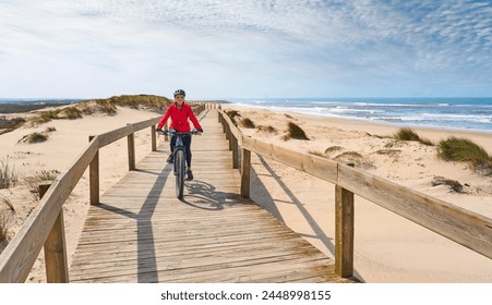 happy active senior woman cycling during moody golden hour at the beach of the atlantic coast below Barra Lighthouse near Aveiro, Portugal Aveiro, Portugal - Powered by Shutterstock