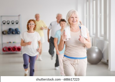 Happy Active Seniors Exercising Together In White Spacious Room