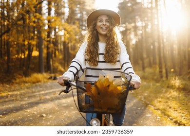 Happy active woman in stylish clothes rides a bicycle in an autumn park at sunset. Outdoor portrait. Beautiful woman enjoying nature. Active lifestyle. - Powered by Shutterstock