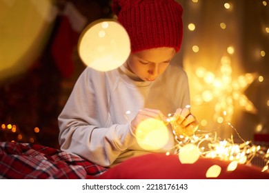 Happy Adorable Cute Kid 10 Years Old Generation Z Preparing Glowing Garland For Christmas At Home. Preparation To Celebrate New Year Gift Giving Around The World Happy Winter Season Time Magic Bokeh