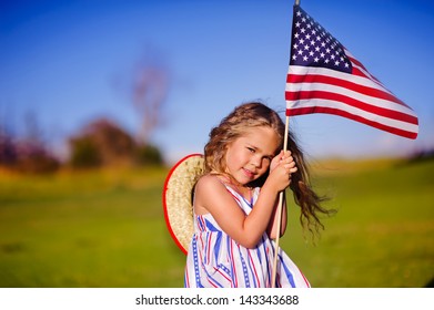 Happy Adorable Little Girl Smiling And Waving American Flag Outside, Her Dress With Strip And Stars, Cowboy Hat. Smiling Child Celebrating 4th July - Independence Day