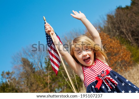 Happy adorable little girl smiling and waving American flag outside