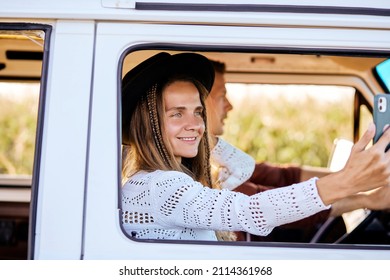 Happy adult beautiful young woman taking photo on smartphone, sitting inside of an old vintage trendy yellow van enjoying the trip, travel lifestyle looking at mobile phone with internet connection. - Powered by Shutterstock