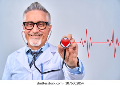 Happy Adult Cardiologist In Uniform Holding Stethoscope And Ready To Consult Patient, Isolated On Grey Background. Healthcare Concept.
Stethoscope In Doctor Hands With Red Cardiogram