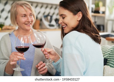 Happy Adult Daughter And Senior Mother Toasting In Wine